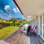 Terrasse mit Sitzgruppe, Garten und Bergblick.