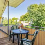 Terrasse mit Tisch und zwei Stühlen, Blick auf grüne Bäume und Häuser.