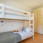 Kinderzimmer mit Doppelstockbett, Kleiderschrank und Wanddekoration.
