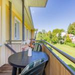 Terrasse mit Tisch und Stühlen, Blick auf grünen Garten und Bäume.