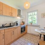 Küche mit Essbereich, Fenster, Küchengeräten und Tisch mit Tassen.