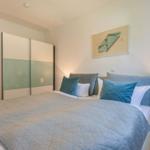 Schlafzimmer mit Bett, Nachttisch und Kleiderschrank.