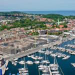 Hafen mit Booten, städtische Umgebung und Bauarbeiten am Ufer.