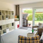 Wohn- und Essbereich mit Bücherregal, TV und Balkontür.