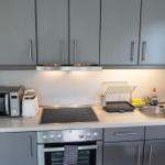 Küche mit grauen Schränken, Herd, Spüle und Küchengeräten.