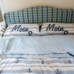 Schlafzimmer mit Bett, Kissen und Decke im nautischen Stil.