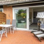 Terrasse mit Sitzgruppe, Strandkorb und Blick in die Küche.