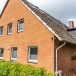 Rotes Backsteinhaus mit Dachgaube und grünem Heckgarten.