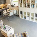 Wohnung mit Küche, Esstisch und Wohnbereich mit Plaid-Sofa und Fernseher.