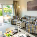 Wohnzimmer mit Plaidsofa, Esstisch und Terrassenzugang.