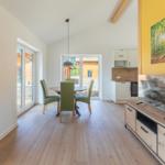 Wohn- und Essbereich mit Holzboden, TV und Küchenbereich.