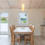 Essbereich mit Holztisch, Stühlen und Küchenzeile. Durchgang zur Wohnfläche mit Sofa.