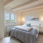 Schlafzimmer mit Bett, Fenster und Deckenbalken.