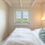 Schlafzimmer mit Doppelbett, Fenster und Holzdecke.