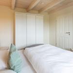 Schlafzimmer mit Bett, Kleiderschrank und zwei Stühlen an den Betten.