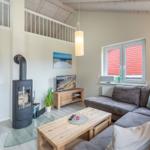 Wohnzimmer mit Sofa, Kamin und Fenster mit roten Jalousien.