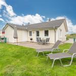Wohnhaus mit Garten, Liegestühlen und Grillplatz unter blauem Himmel.