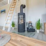 Wohnbereich mit Holzofen, Fernseher und Treppe zur Galerie.