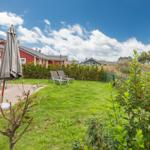 Hinterhof mit Garten, Liegestühlen und Terrasse unter blauem Himmel.