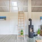 Wohnraum mit Holztreppe zur Galerie, Kamin und TV.