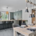 Essbereich mit rustikalem Tisch und moderner Küche mit Barhocker.