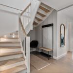 Haus mit Treppe, Garderobe und Spiegel. Durchgang zu Essbereich mit Tisch und Stühlen.