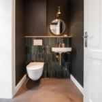 Hochwertige Toilette und Waschbecken mit Spiegel und goldfarbenen Armaturen.