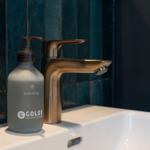 Waschbecken mit goldenem Wasserhahn und Seifenspender.