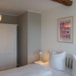 Schlafzimmer mit Bett, Schrank und Wandbildern.