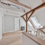 Haus mit Holzdeckenbalken, Treppenhaus und Dachfenster. Flur mit Holzboden und Türen.