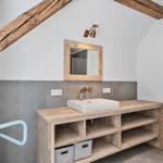 Badezimmer mit Holzwaschtisch, Spiegel und Dachschrägen.