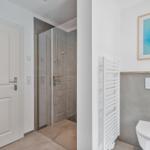 Badezimmer mit Dusche, Toilette und Heizkörper.