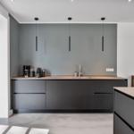 Moderne Küche mit grauen Schränken, Arbeitsplatte und Fensterblick.