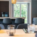 Essbereich mit Tisch, Stühlen und Blick auf grüne Bäume.