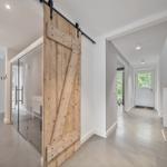 Eingangsbereich mit Holzschwingtür und Glaswand. Helle Wände und Boden.