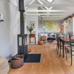 Wohn- und Essbereich mit Holzboden, Kamin und großem Fenster