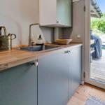 Küche mit Holzplatte, Edelstahlspüle und Blick auf die Terrasse.