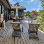 Terrasse mit Holzdielen, Stühlen und Blick auf grüne Landschaft.