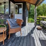 Terrasse mit Stuhl, Tisch und Pflanzen. Hintergrund: Haus und Grün.