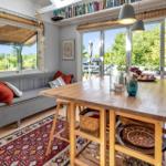 Ein Raum mit Holztisch, Sofa und Blick auf die Terrasse.