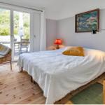 Schlafzimmer mit Bett, Stuhl und Blick auf Terrasse.