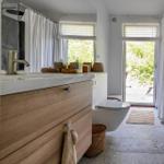 Badezimmer mit Waschbecken, Toilette und Dusche. Durchgang zur Terrasse mit Blick auf Grün.