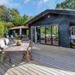 Holzterrasse mit Sitzgelegenheiten und Blick auf das Haus.