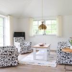 Wohnzimmer mit Sitzgruppe, Tisch und Fenstern.