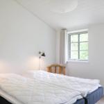 Schlafzimmer mit Bett, Fenster und Tür zur Außenterrasse.