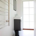 Badezimmer mit Handtuchhalter, Waschbecken und Fenster.