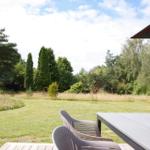 Terrasse mit Tisch und Stühlen, Blick auf grünen Rasen und Bäume.