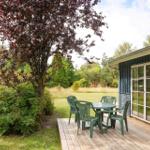 Terrasse mit grünem Tisch und Stühlen neben blauem Haus mit Gartentür.