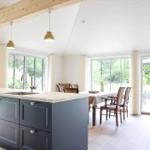 Küche mit Kücheninsel, Essbereich und großzügigen Fenstern.