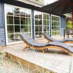 Terrasse mit zwei Liegestühlen, Sonnenschirm und Tisch mit Stühlen.